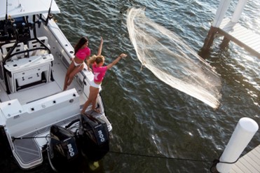 Two girls casting a fishing net off their center console Blackfin fishing boat