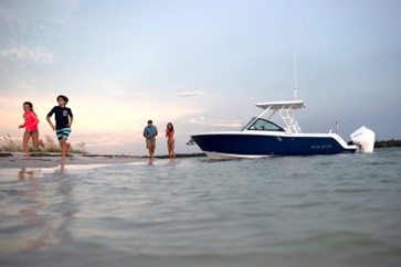 Family on a shoreline with their Blackfin dual-console boat at sunset